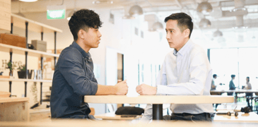 Image of two young professionals talking in a open area in office building 
