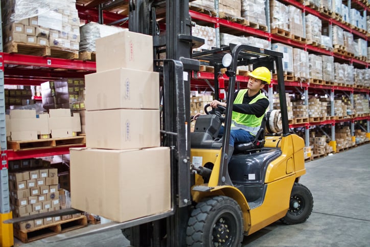 Man moving load with forklift loader in warehouse