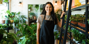 Young worker in a flower shop standing near a ladder.