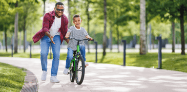 Parenting helping a child learn to ride a bike.