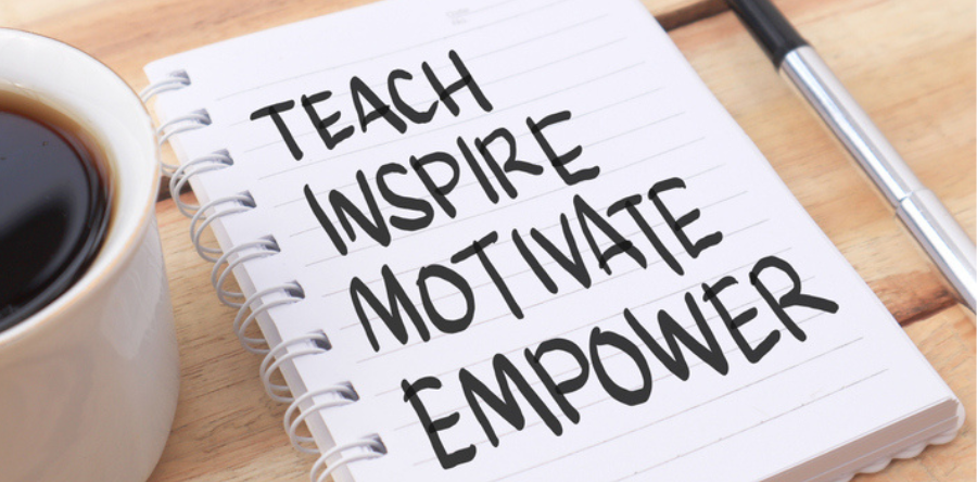Notepad with Teach, Inspire, Motivate and Empower written on white paper on a desk beside a cup of coffee and pen