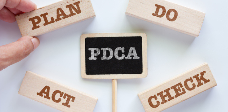 Plan, do, act, check written on wooden blocks and PDCA written on a chalk board