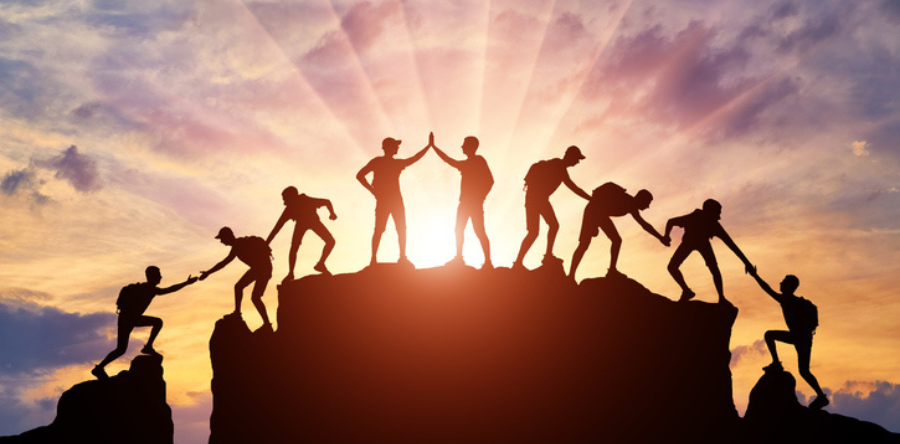 Image of a silhouette person climbing up and down a mountain with a sunset