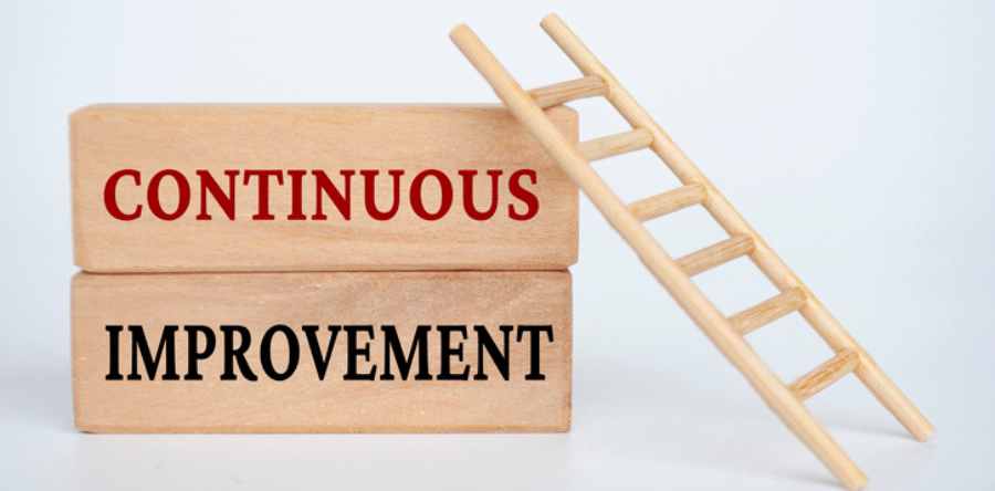 Stacked wooden blocks labeled with continous improvment with a ladder resting on side