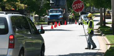 Teen holding a stop sign at work on a road.
