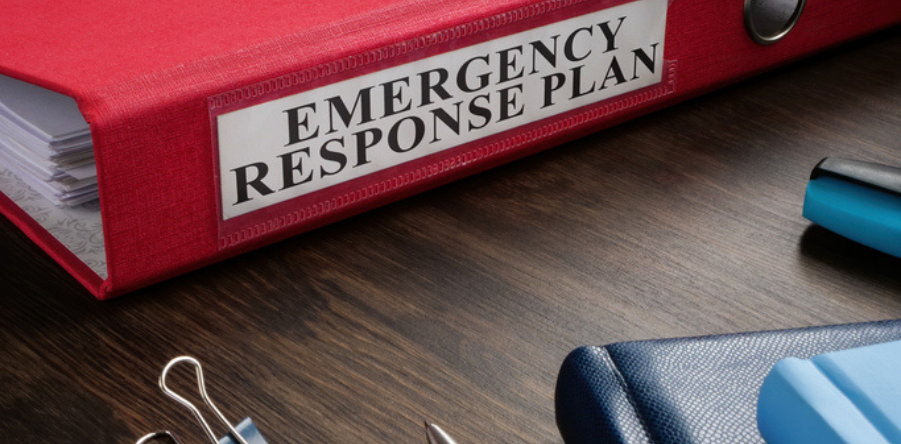 A Red folder with Emergency response plan on the desk.