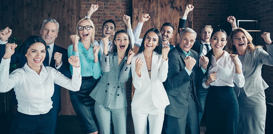 A group mixed races of male and female co-workers standing in a room cheering