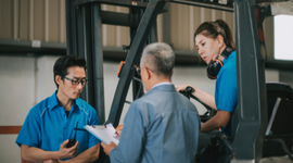 Image of 3 workers in a warehouse reviewing and discussing a checklist 