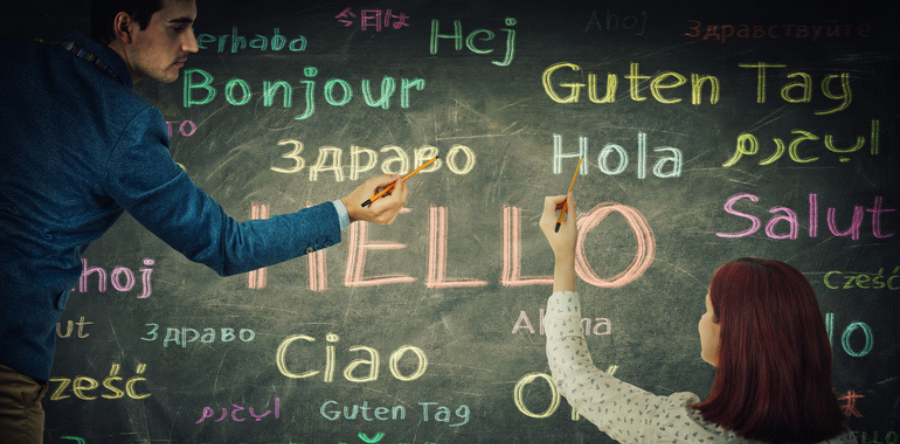 Man and woman together drawing word hello in different languages and colors on blackboard