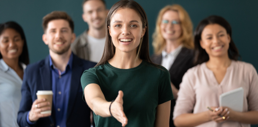Image of male and female co-workers standing in a room with one person hand in a handshake position