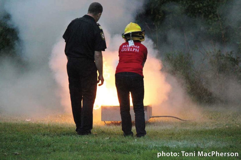 Photo taken by Toni MacPhearson | Equine Guelph worker being taught by fire ser correct way to extinuish a fire using a handheld extinguisher on a live fire