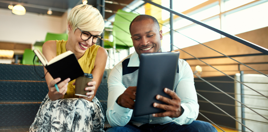 Image of two co-workers sitting on stairs reviewing notes from books