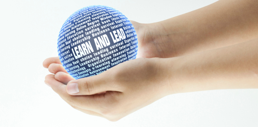 IImage of hands cupped together holding a blue and white ball with learn and lead written on ball in white.