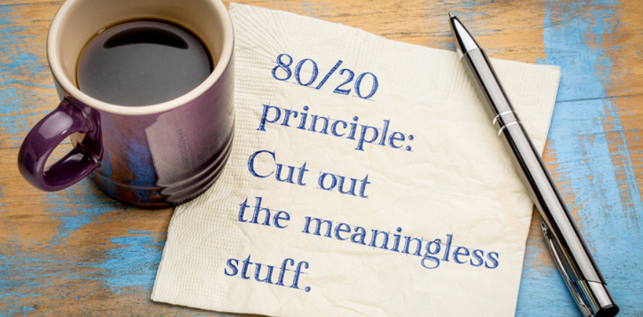 Image of a coffee mug with a pen on table with napkin written with 80/20 principle cut out the meaningless stuff