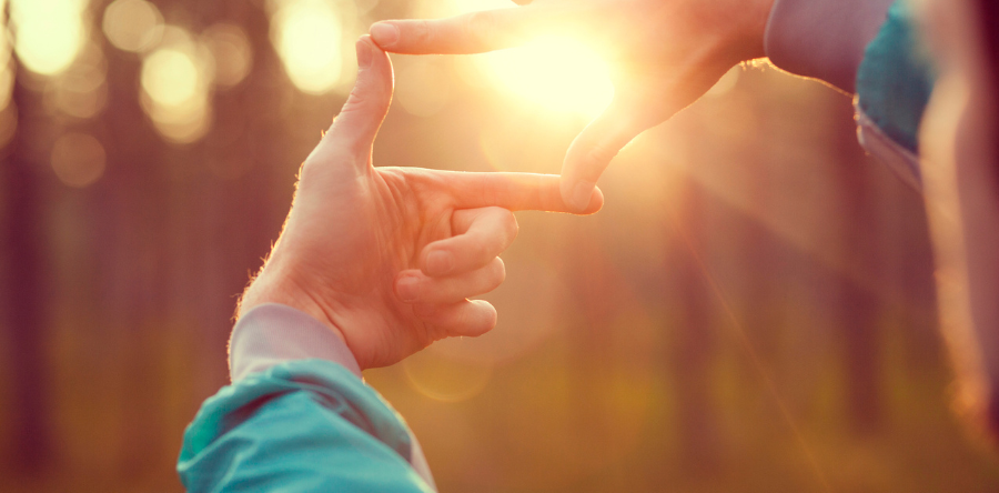 Image of person using there hands to create a frame around the sun